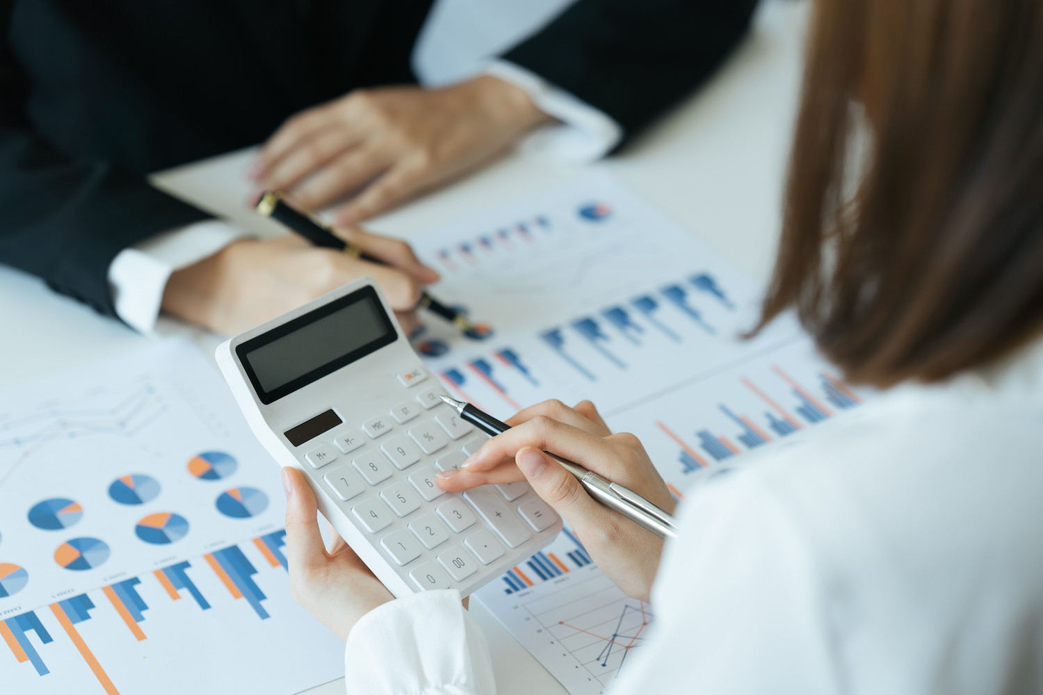 Financial adviser working with client, calculating and analyzing data at the table in office.